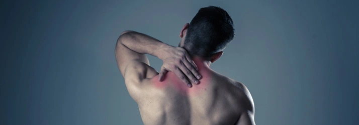 A person holding the back of the neck with visible redness, illustrating upper back or neck pain.